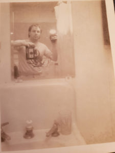 Tim Mays photographs himself in bathroom mirror